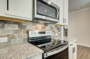 backsplash and granite countertops with stove and microwave