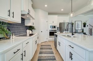 kitchen walkway with blue tiles and white cabinets