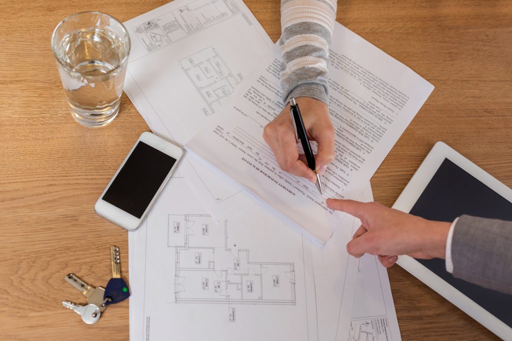 Top Questions to Ask Your Builder Before Signing a Contract, High angle view of saleswoman pointing at form to woman in apartment
